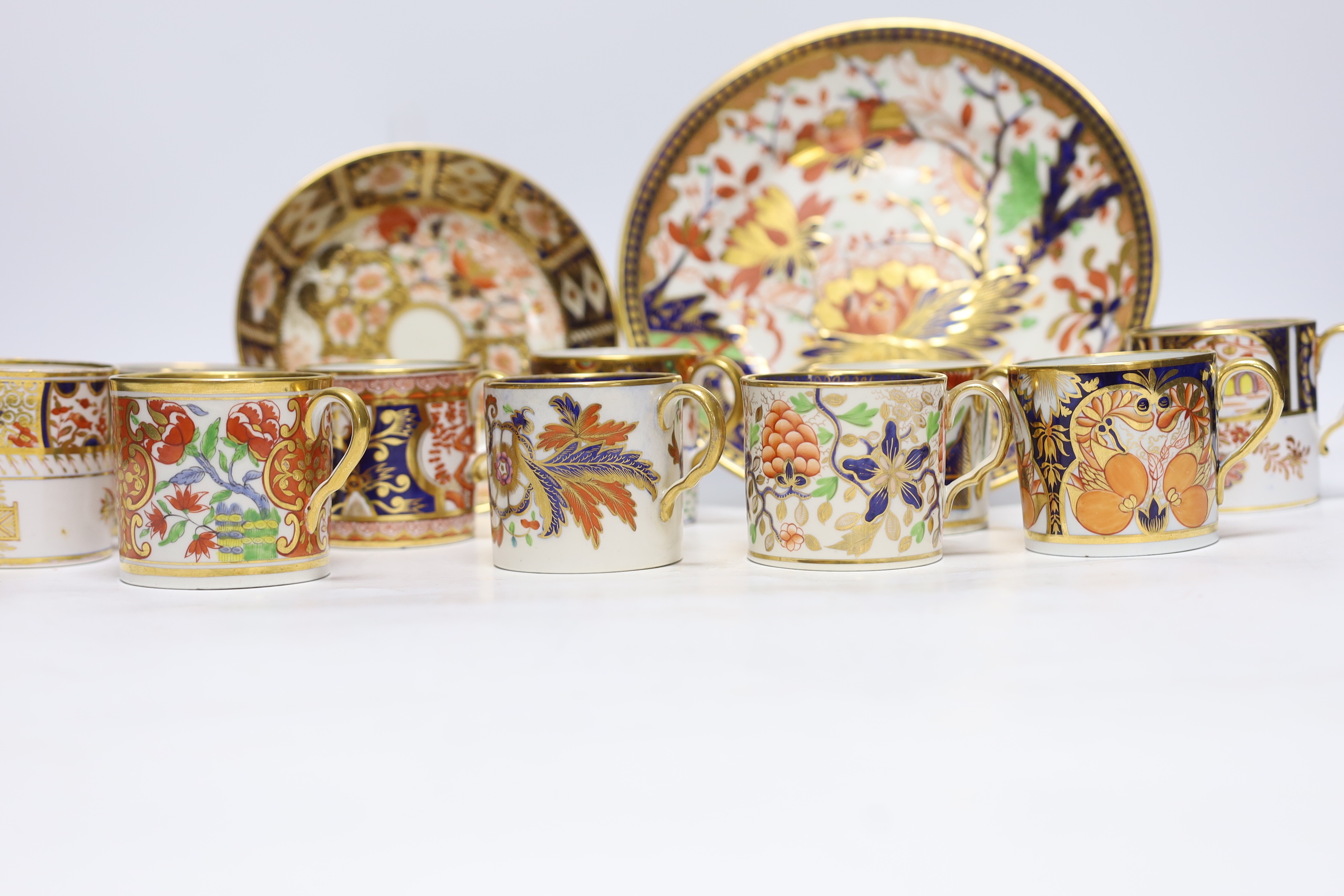 Ten 1800-1820 English porcelain coffee cans, including Imari pattern examples, one with matching saucer, together with a side plate (12)